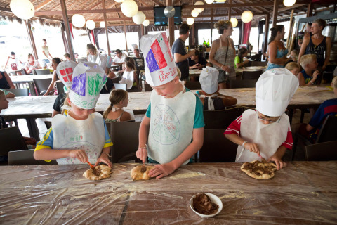 Bambini preparano la pizza indossando cappelli da chef durante un’attività al Altomincio Family Park in Italia.
