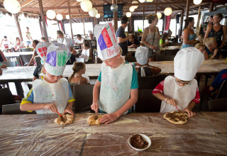 Bambini preparano la pizza indossando cappelli da chef durante un’attività al Altomincio Family Park in Italia.