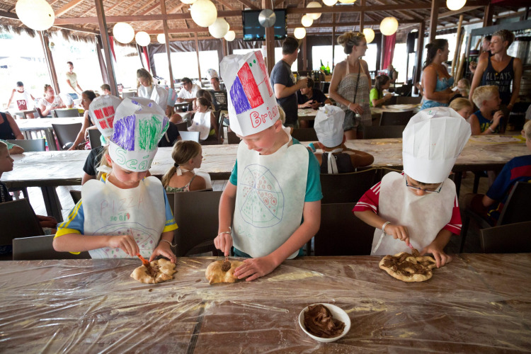 Children making pizza and wearing chef hats during a kids’ activity at Altomincio Family Park in Italy.