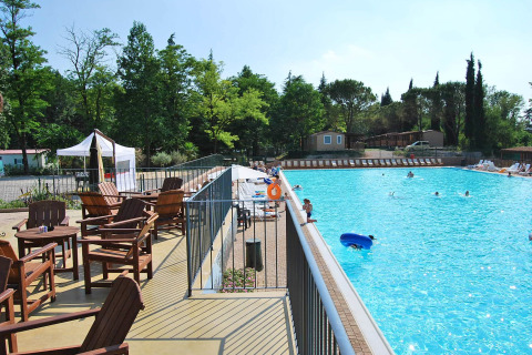 Piscina soleada con sillas de madera y vistas verdes en Altomincio Family Park, Lombardía, Italia.