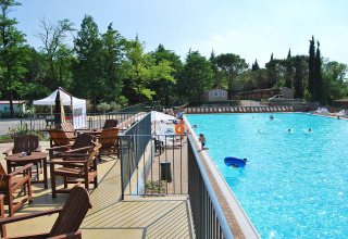 Solrig swimmingpool med træmøbler og grønt landskab, Altomincio Family Park, Lombardiet, Italien.