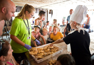 Children and adults gather around a table with pastries during a cooking activity at Altomincio Family Park.