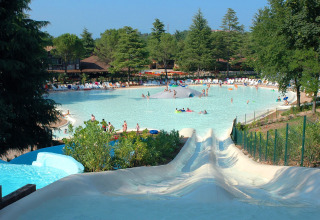 Vandrutsjebaner ved en stor swimmingpool fyldt med familier, omgivet af grønne træer i Altomincio Family Park.
