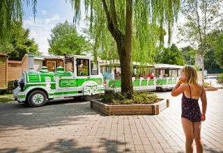 Una bambina in costume osserva un trenino turistico verde e bianco all’Altomincio Family Park, Lombardia, Italia.