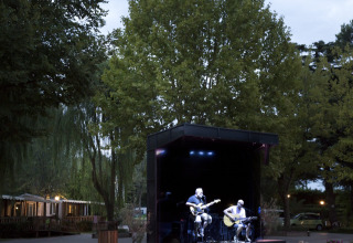 Concerto all'aperto all'Altomincio Family Park in Lombardia, Italia, musicisti si esibiscono sul palco al tramonto.