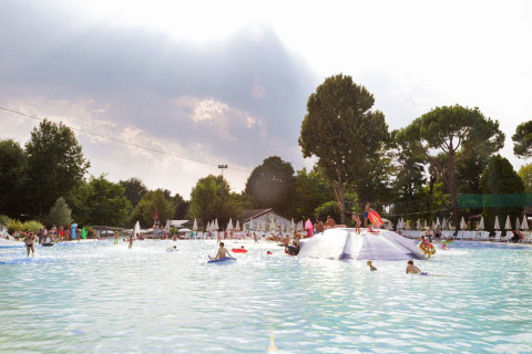 Children and families enjoy a large swimming pool with loungers at Altomincio Family Park in Lombardy, Italy.