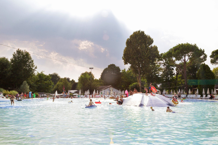 Children and families enjoy a large swimming pool with loungers at Altomincio Family Park in Lombardy, Italy.