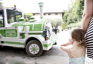 Bambina si tappa le orecchie mentre un trenino verde e bianco passa all’Altomincio Family Park, Italia.