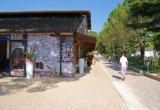 Pathway at Altomincio Family Park in Lombardy, Italy, with people walking beside a building and green trees.