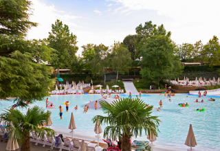 Børn og familier nyder en stor swimmingpool omgivet af grønne træer i Altomincio Family Park, Lombardiet, Italien.