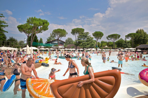 Familias disfrutan de un día soleado en la piscina llena de flotadores en Altomincio Family Park, Lombardía.