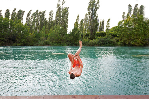 Een jongen springt in het water in Altomincio Family Park, Lombardije, Italië, omgeven door groene bomen.