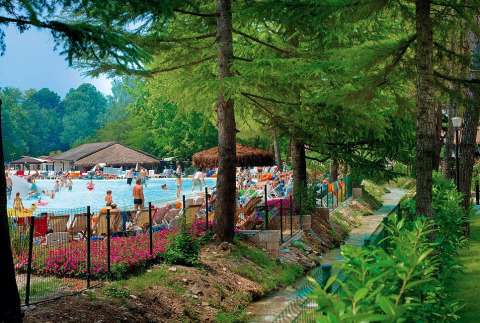 Udendørs poolområde på Altomincio Family Park, Lombardiet, Italien, omgivet af grønne træer og blomster.