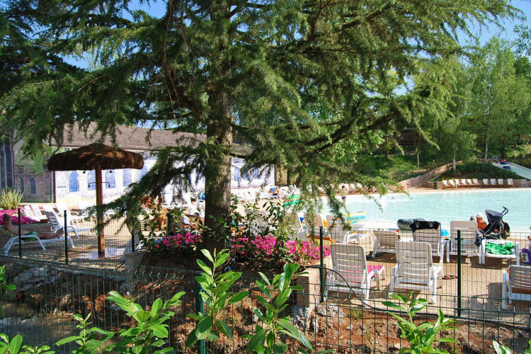 Lounge chairs and umbrellas by a pool surrounded by trees at Altomincio Family Park, Lombardy, Italy.