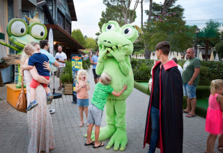 Bambini e adulti incontrano una mascotte rana all'Altomincio Family Park, parco vacanze in Lombardia, Italia.