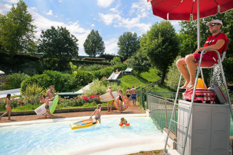 Livredder overvåger børn og familier, der nyder poolen og vandrutsjebaner i Altomincio Family Park, Italien.