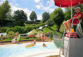Livredder overvåger børn og familier, der nyder poolen og vandrutsjebaner i Altomincio Family Park, Italien.
