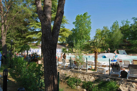 Vue sur Altomincio Family Park en Lombardie, Italie, avec piscine, transats et arbres verdoyants autour.