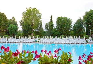 Piscina esterna presso Altomincio Family Park in Lombardia, Italia, circondata da lettini, ombrelloni e alberi.