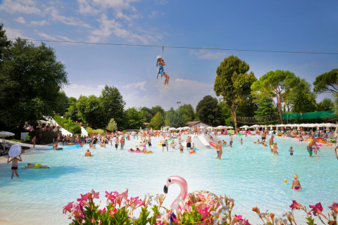 Familias y niños disfrutan de la piscina y la tirolesa en Altomincio Family Park en Lombardía, Italia.