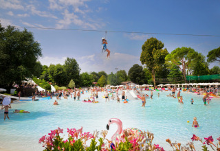 Kinderen en ouders beleven plezier aan het zwembad en de zipline in Altomincio Family Park, Lombardije.