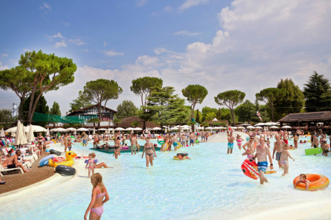Familias disfrutan de la piscina al aire libre en Altomincio Family Park, Lombardía, Italia, en un día soleado.