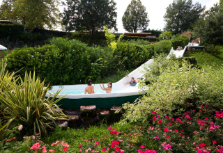 Bambini si divertono su uno scivolo d'acqua immerso nel verde all'Altomincio Family Park, Lombardia.