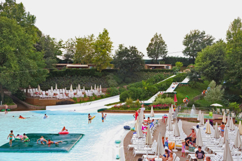 Piscina y toboganes acuáticos en Altomincio Family Park, Italia, rodeados de tumbonas y jardines verdes.