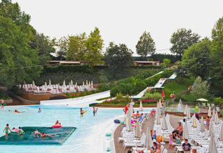 Piscina e scivoli d'acqua al Altomincio Family Park in Italia, con ospiti e numerosi lettini rilassanti.