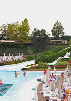 Piscina y toboganes acuáticos en Altomincio Family Park, Italia, rodeados de tumbonas y jardines verdes.