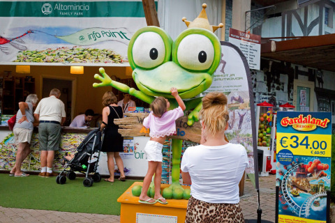 Un niño toca una gran estatua de rana en Altomincio Family Park, un parque de vacaciones familiares en Lombardía, Italia.