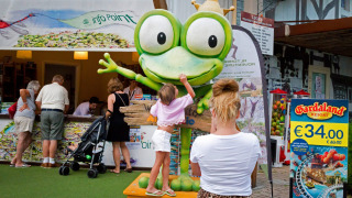 Un niño toca una gran estatua de rana en Altomincio Family Park, un parque de vacaciones familiares en Lombardía, Italia.