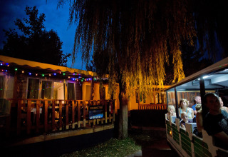 Avondzicht op Altomincio Family Park, Lombardije, Italië, met vakantiehuisjes en bezoekers in een treintje.