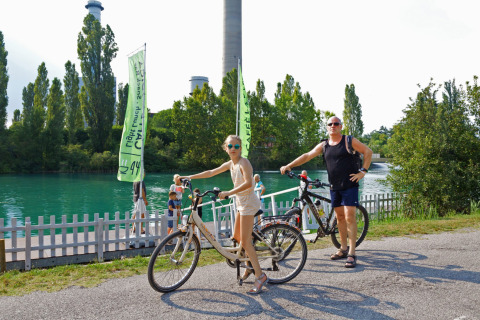 Twee personen poseren met fietsen aan het water in Altomincio Family Park, Lombardije, Italië.