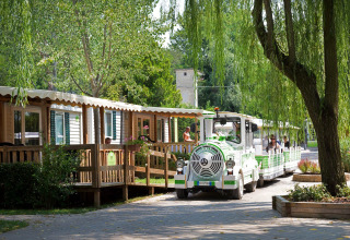 Et lille turisttog kører forbi mobilhomes i Altomincio Family Park omgivet af grønt i Lombardiet, Italien.
