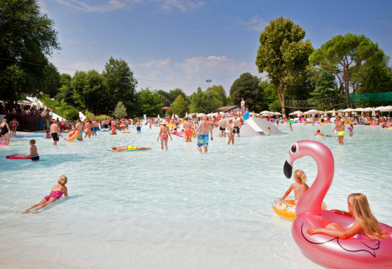 Children and families play in a shallow swimming pool at Altomincio Family Park, Lombardy, Italy.