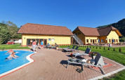 Camping Bella Austria feriepark i Stiermarken, Østrig, med gul bygning, pool, liggestole og gæster i solskin.