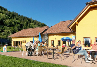 Udendørs spisning ved Camping Bella Austria, feriepark i Stiermarken, Østrig, omringet af natur.