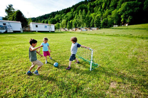 Niños jugando al fútbol en un campo de césped en Camping Bella Austria, parque de vacaciones en Estiria, Austria.