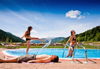 Bambini giocano vicino alla piscina tra le montagne al Camping Bella Austria in Stiria, Austria.