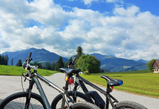 Due biciclette su una strada con vista su montagne e prati al Camping Bella Austria in Stiria, Austria.