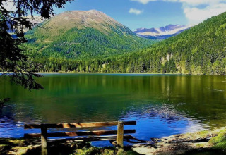 Panchina davanti al lago e alle montagne verdi al Camping Bella Austria, Stiria, Austria.