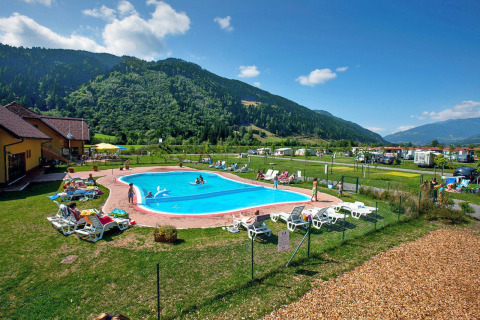 Piscine extérieure et transats avec vue sur les montagnes au Camping Bella Austria en Styrie, Autriche.