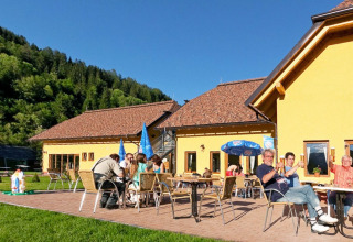 Guests enjoying outdoor dining and sunshine at Camping Bella Austria holiday park in Styria, Austria.