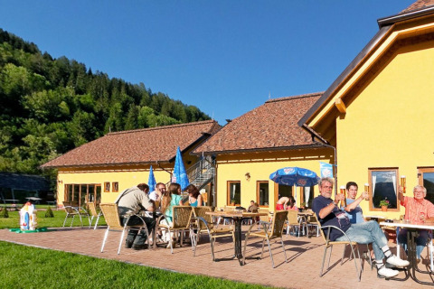 Ferieparkgæster nyder solskin og udendørs spisning ved Camping Bella Austria i Stiermarken, Østrig.