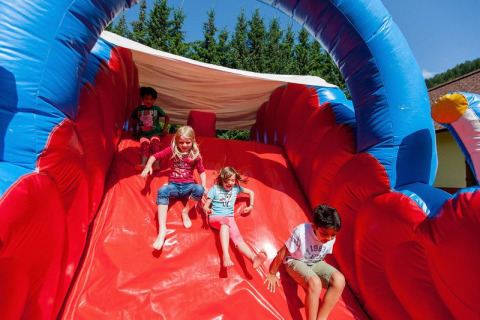 Niños deslizándose por un tobogán inflable en Camping Bella Austria, parque vacacional en Stiermarken, Austria.