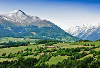 Berglandschap nabij St. Peter am Kammersberg, Oostenrijk, met groene heuvels en met sneeuw bedekte toppen.