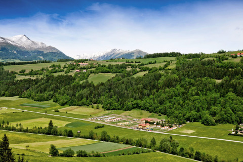 Panoramaudsigt over Camping Bella Austria i Stiermarken med frodige bakker og sneklædte bjerge bagved.