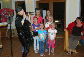 Gruppo di bambini con una cantante durante una serata di intrattenimento al Camping Bella Austria in Stiria.