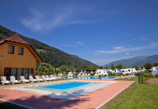 Piscina exterior con tumbonas y vistas a las montañas en Camping Bella Austria, Estiria, Austria.
